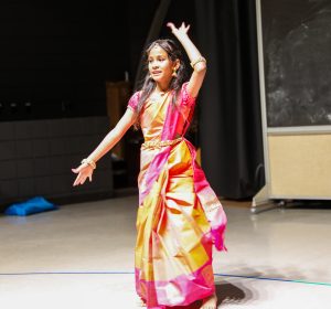 Young girl in traditional Indian attire performing a dance on stage.