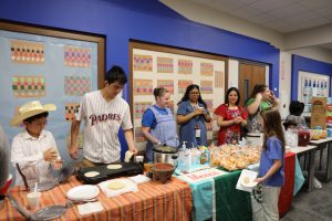 People gathered around a table with food, including pizza and drinks, in a room decorated for an event.