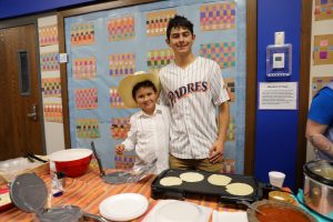 Two people standing in front of a table filled with food.