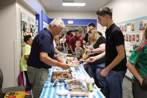 People gathered around a table filled with food at an event.
