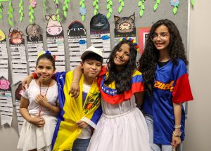 Three people posing in front of a classroom bulletin board decorated for a school event.