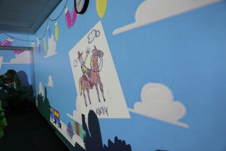 A colorful mural on a wall featuring cartoon-like illustrations of a horse and rider, a castle, and a blue sky background.