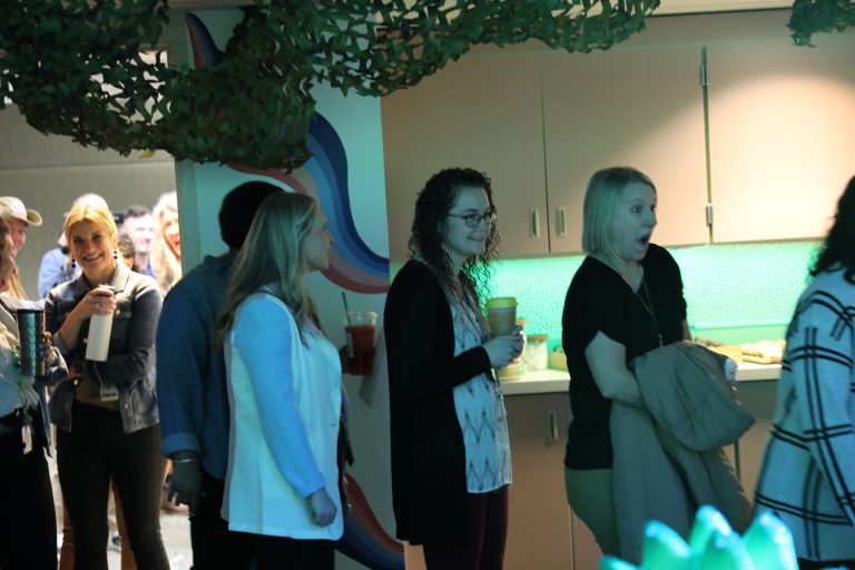 People standing in a line at an event, looking to their left, possibly waiting for something or someone.