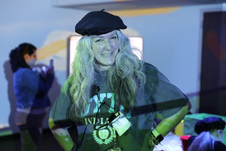 Woman in black hat posing at event, smiling and looking directly at camera.