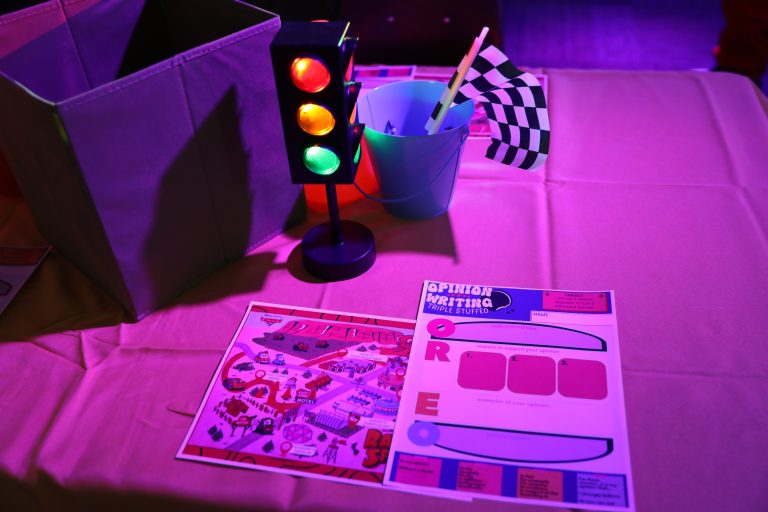 Tabletop display of children's toys and a race car set against a purple backdrop.