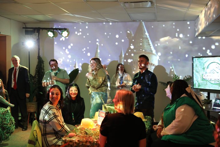 People gathered around a table in a room, celebrating an event, with a projection of snowflakes and a castle on the wall