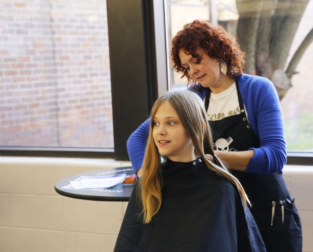 PHM student getting hair cut for "Short Hair Because we Care" hair donation event