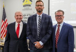 Three men standing in suits smiling