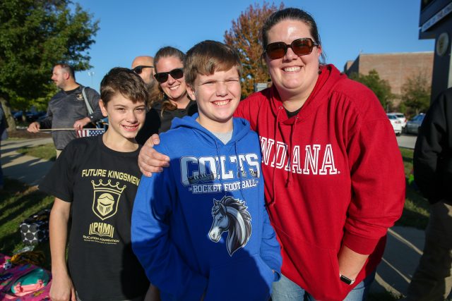 Woman in red sweatshirt posing with boy at a sports event.
