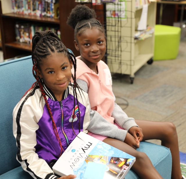 two students sitting next to each other on couch in library 