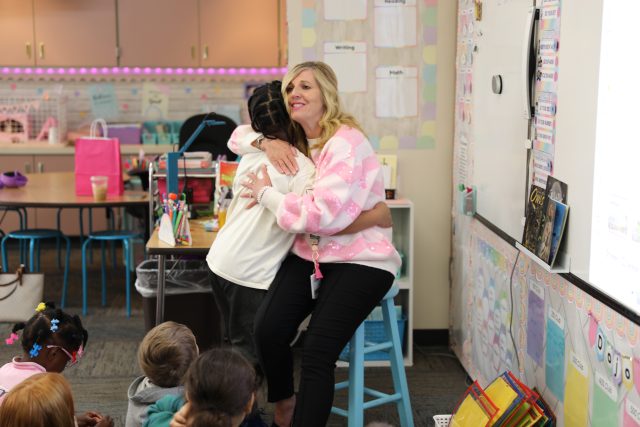 student hugs woman in pink sweater