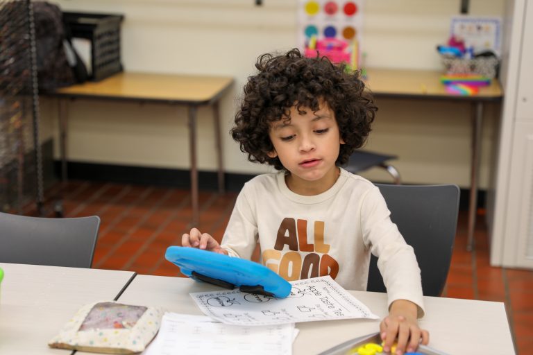 Child sitting at a desk in front of a laptop.