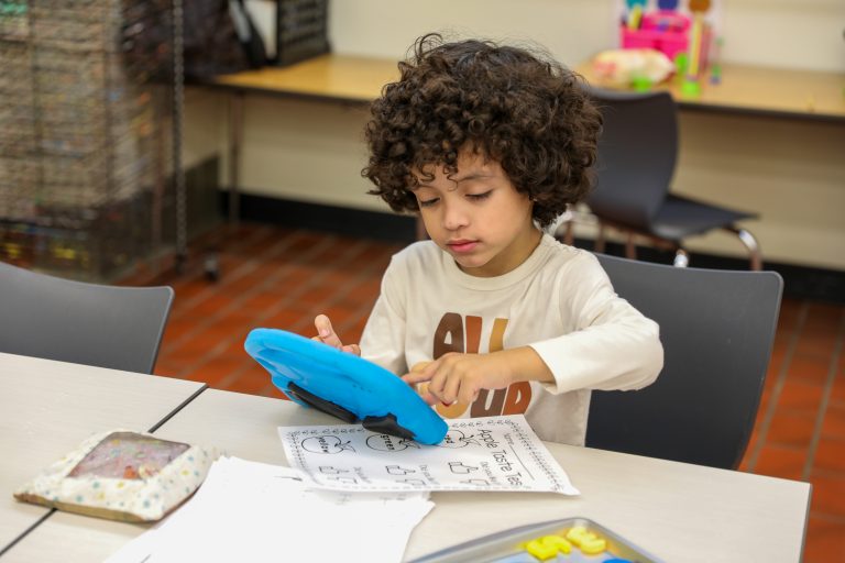 Child sitting at a table with a book in front of him.