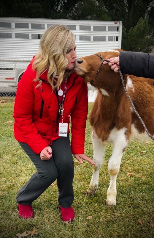 woman in red coat kissing a calf
