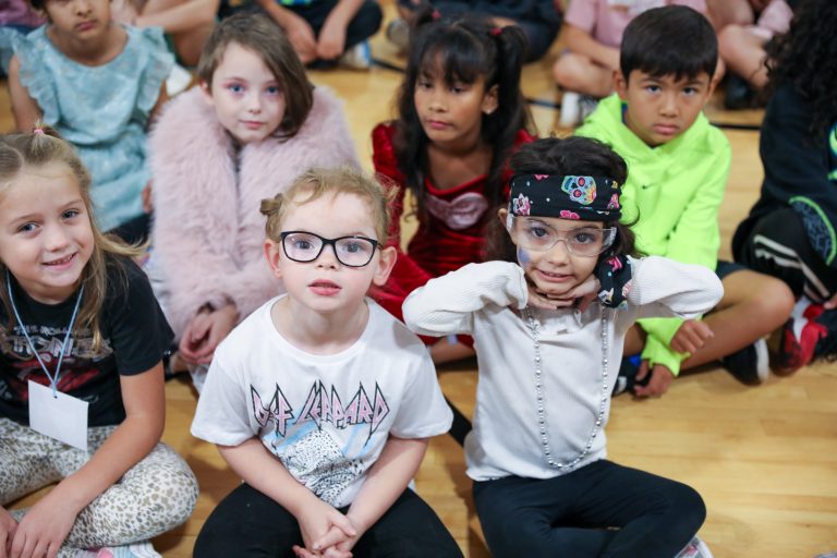 Children posing for a picture in front of a stage.