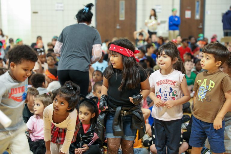 Children in costumes at a school event, posing for a group picture.