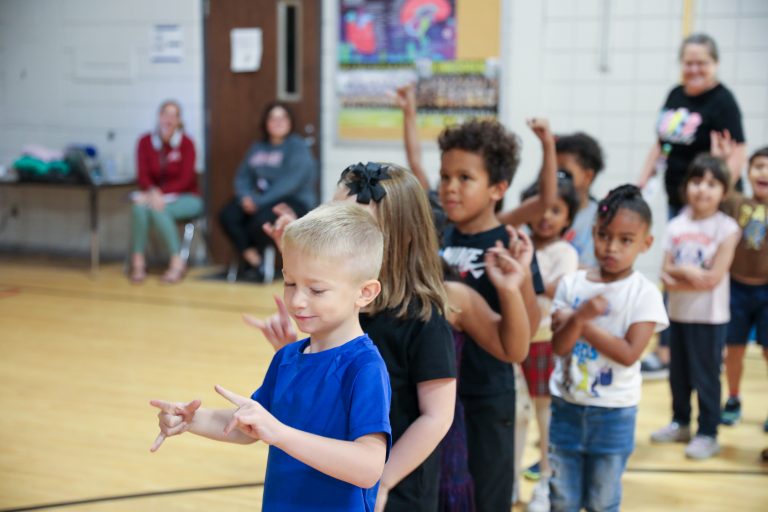 Children in a classroom setting, performing a dance routine.