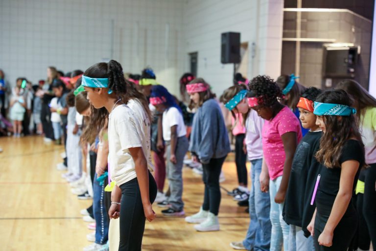 Children in a line wearing colorful headbands.
