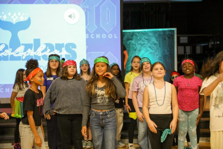 Group of people on stage, some wearing bandanas, others holding signs, all appear to be part of a performance or event.