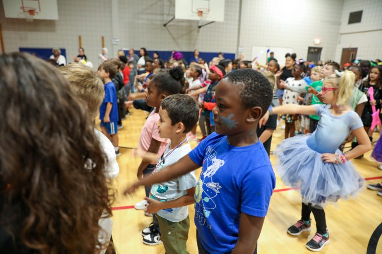 Children dancing in a gymnasium during a party.