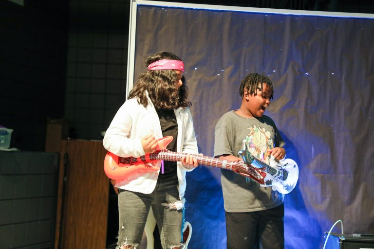 Two people playing guitars on stage.