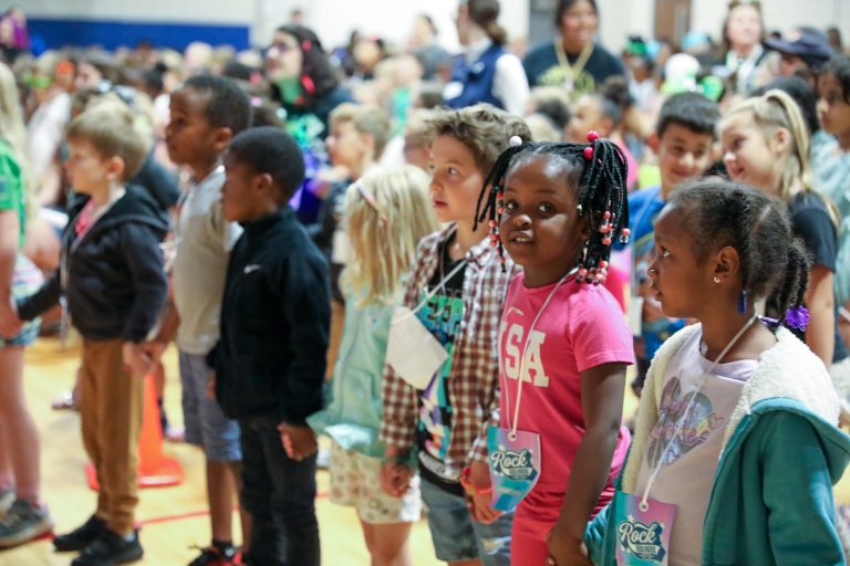Children standing in a line on stage at an event.