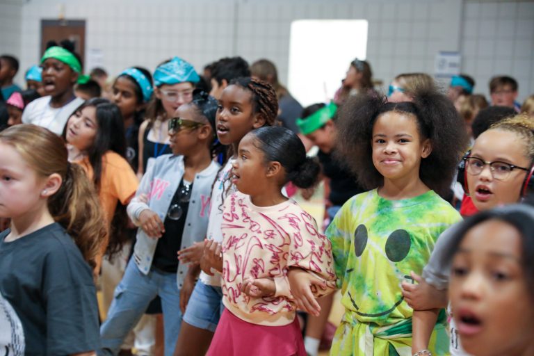 Children dancing in a group at an indoor event.