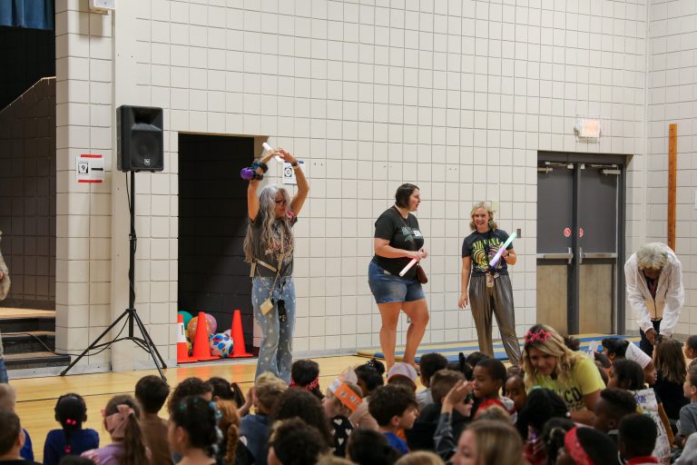 People in a gymnasium performing on stage.