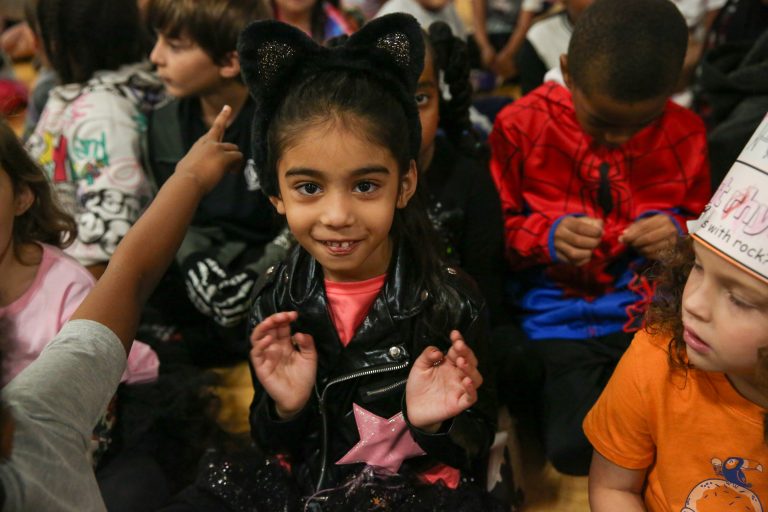 Children in costumes sitting on floor.