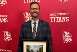 Mr. Matt Garber posing with his IUSB Alumni of the Year award standing in front of an IU South Bend Titans backdrop