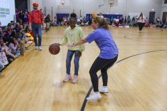 Woman holding a basketball on a gymnasium court.