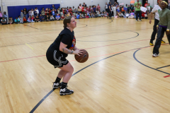 Woman in black shirt holding basketball on court.