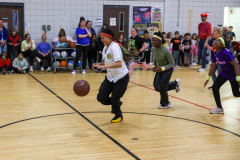 Woman playing basketball in gymnasium.
