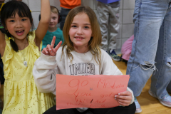 Girl holding a sign in front of a group of children.